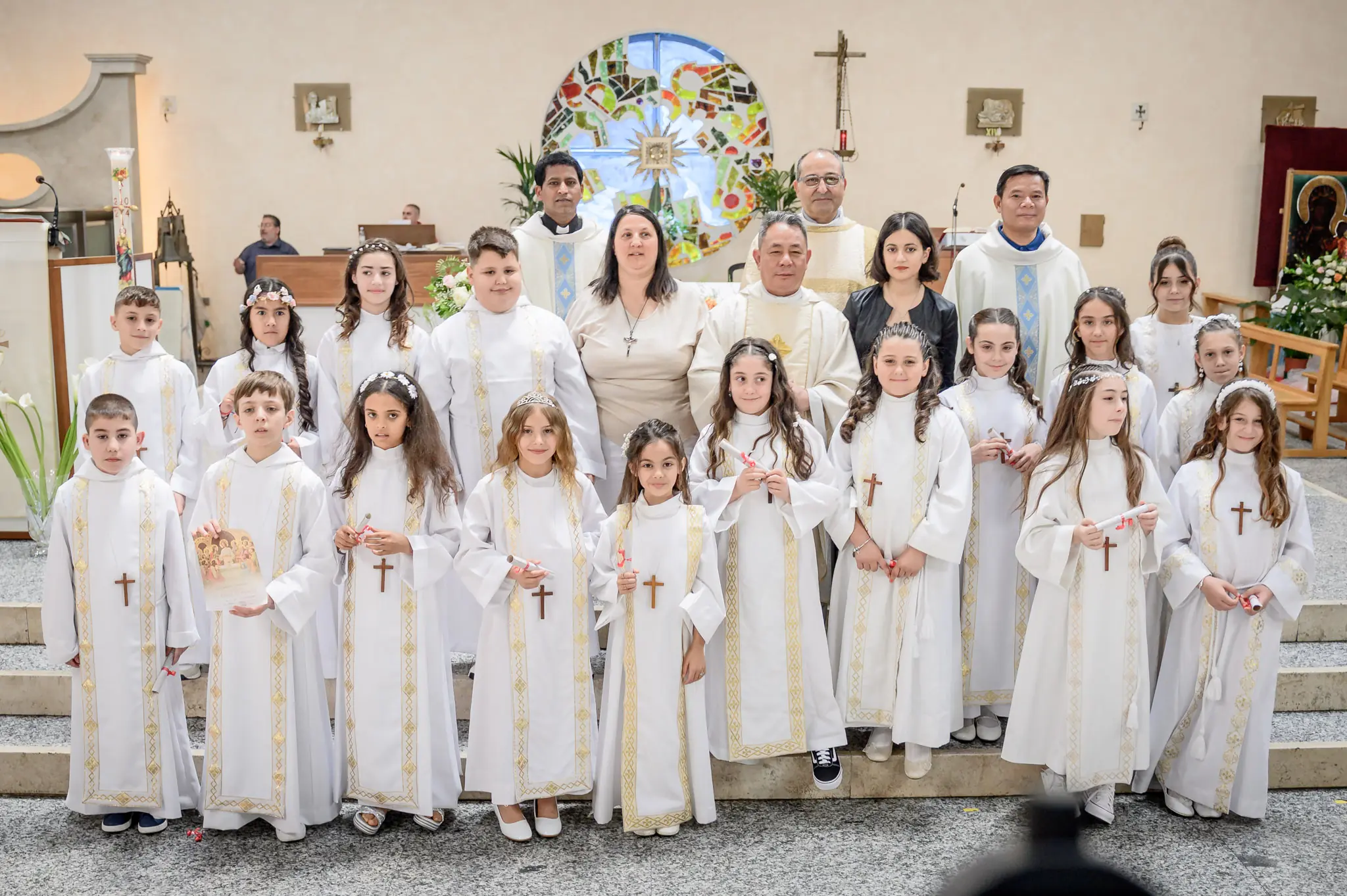 Bambina con la tunica bianca della prima comunione che sorride in chiesa